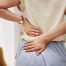 “Woman holding her lower back and hip in pain from prolonged sitting”